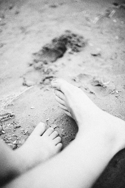 foot in sand with footprints and animal tracks