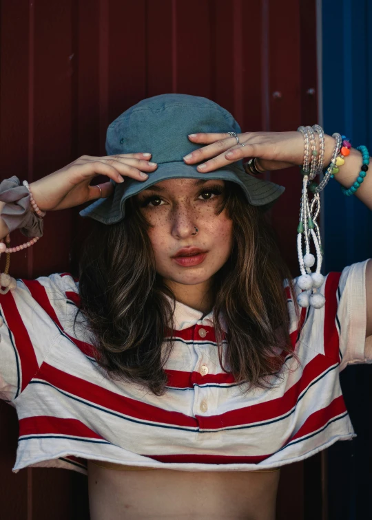 a girl in a striped shirt is holding her hat over her head