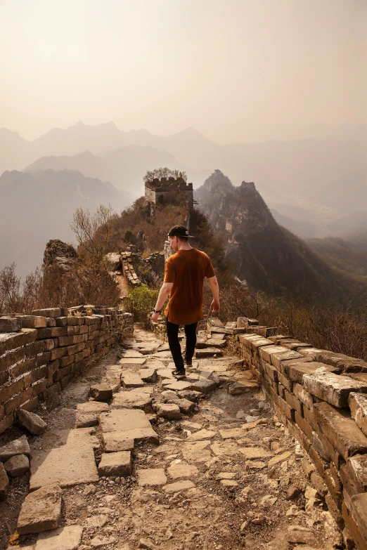 a man walking up the steps of a stone wall