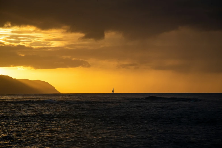 a sailboat in the ocean at sunset