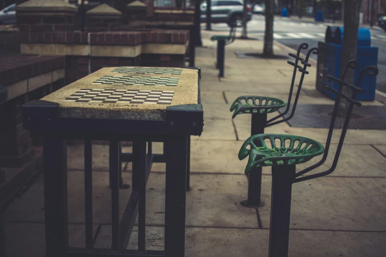 a sidewalk that has three tables with green chairs