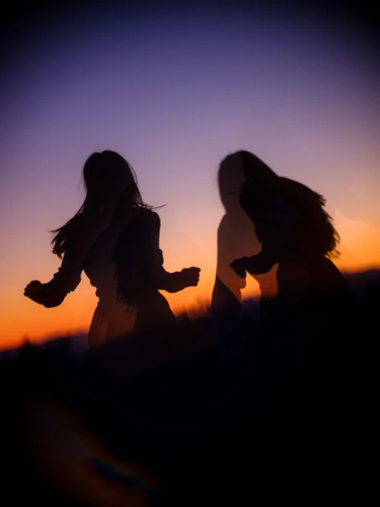 the silhouettes of two people are shown against the evening sky