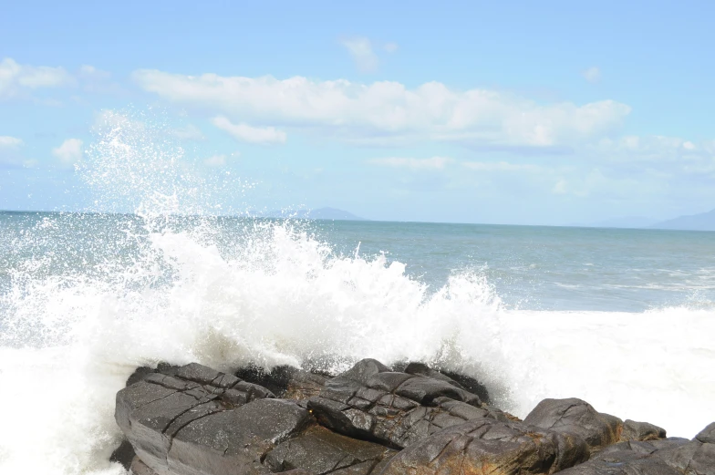 a large wave crashing into some rocks by the ocean