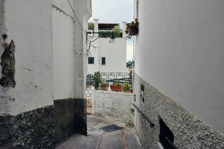 an alley way with a stone wall and white walls