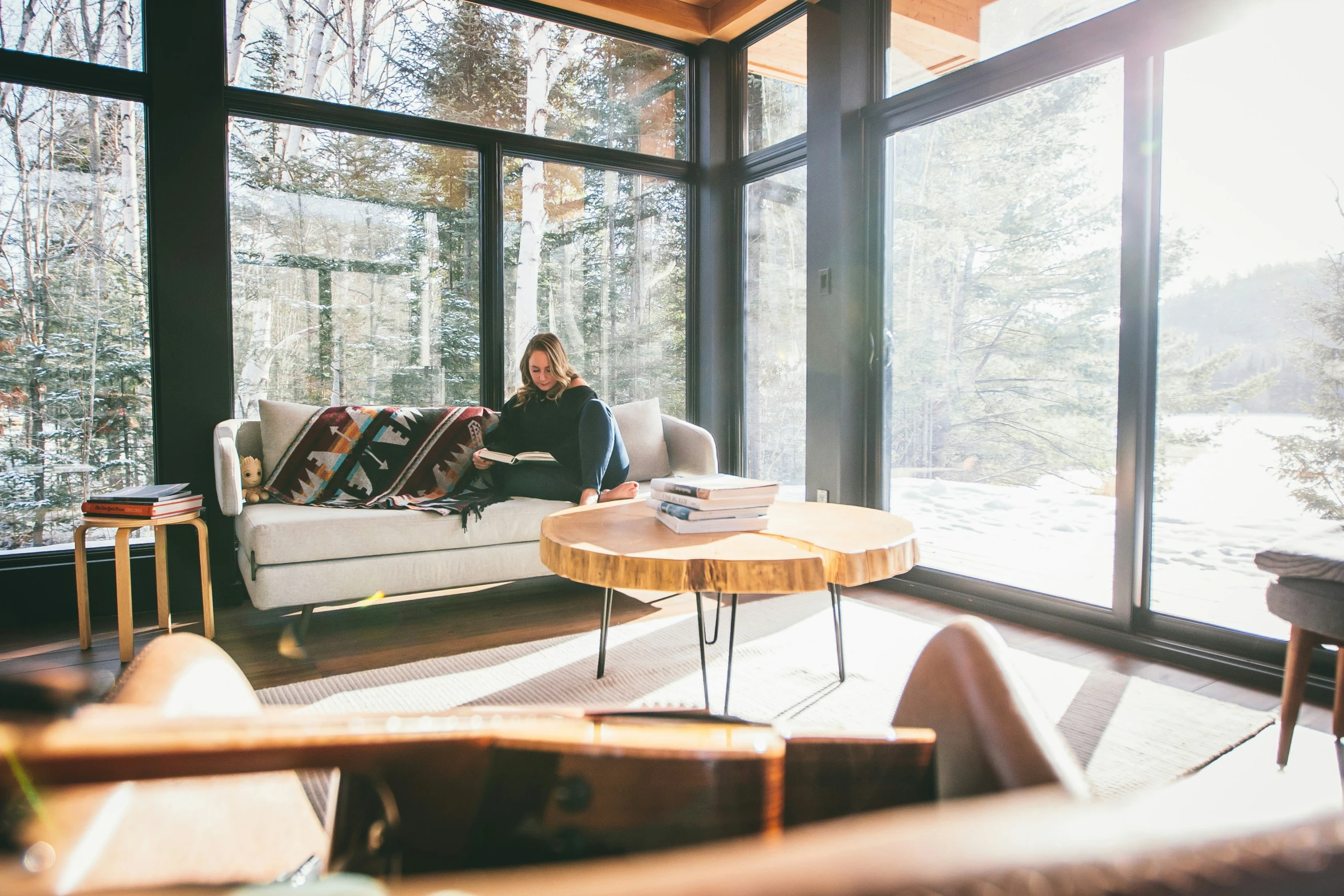 a person sitting on a couch next to a table in front of large windows