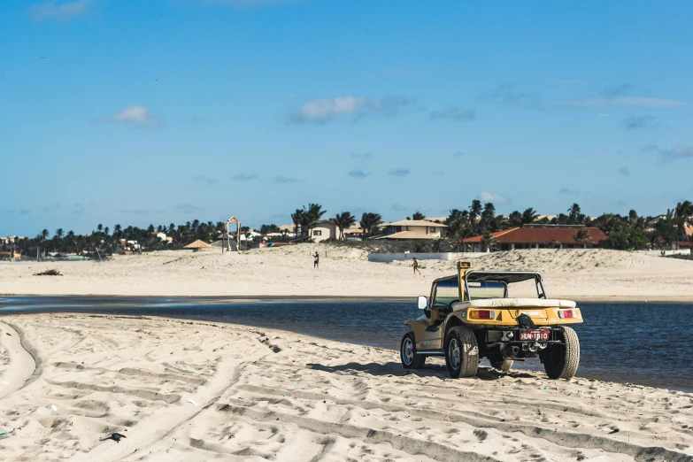 a vehicle drives along the beach next to some water