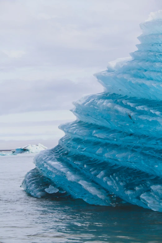 a huge iceberg with many thin icicles and one in the water