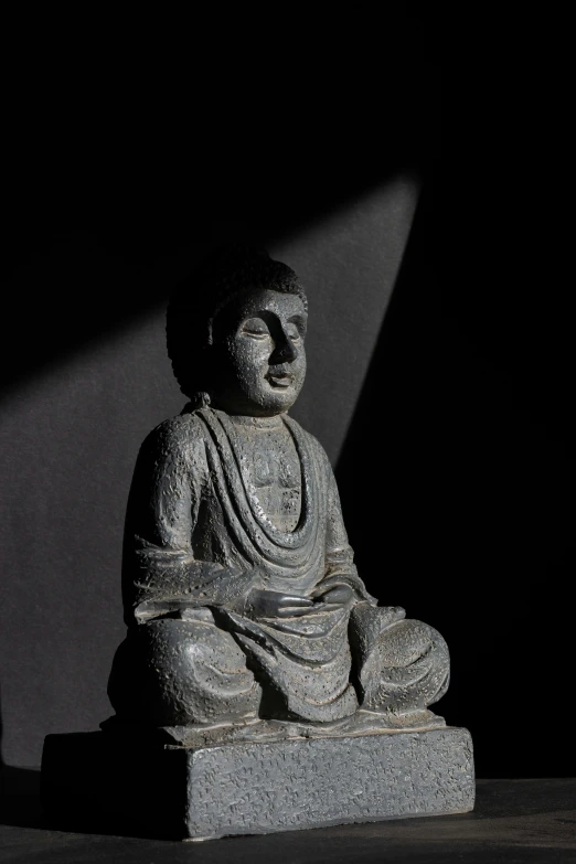 a stone statue that is sitting on a black surface