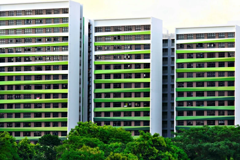 three large white buildings with green windows against a cloudy sky