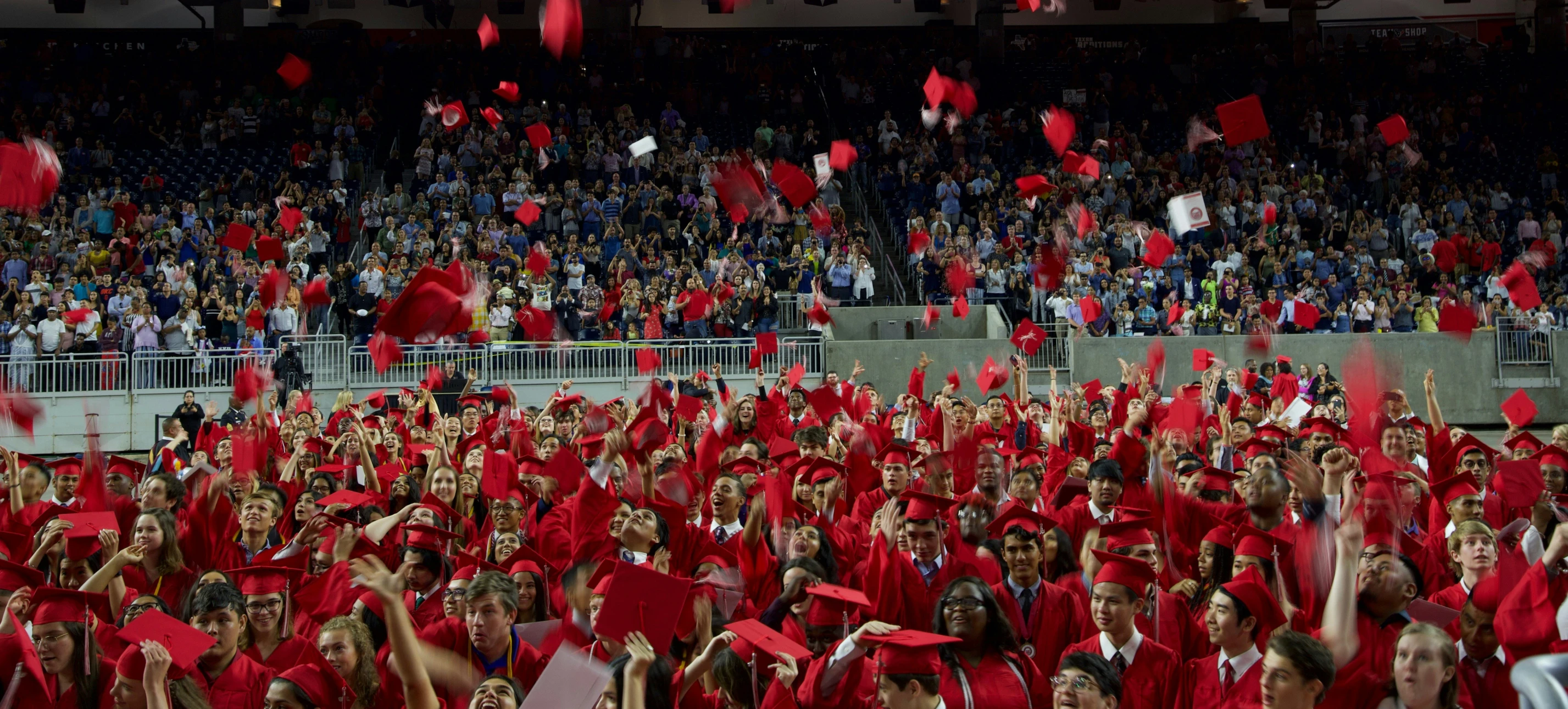 graduates throw their caps in the air in unison