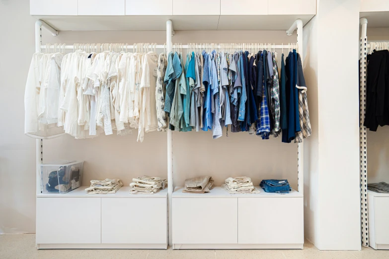 a closet filled with shirts and jackets next to the wall