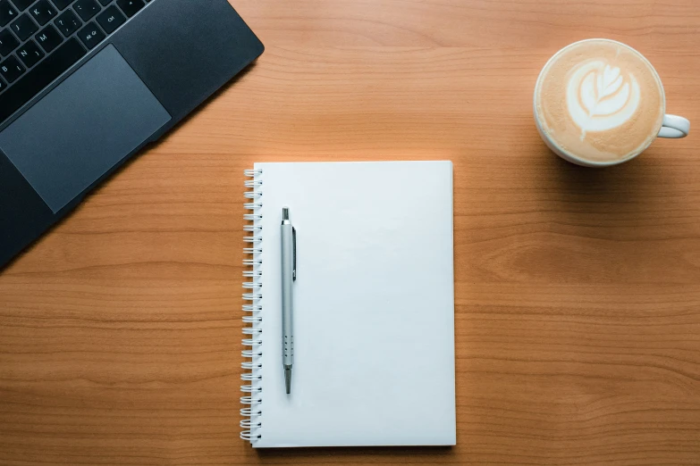 notebook on a wooden desk next to a keyboard