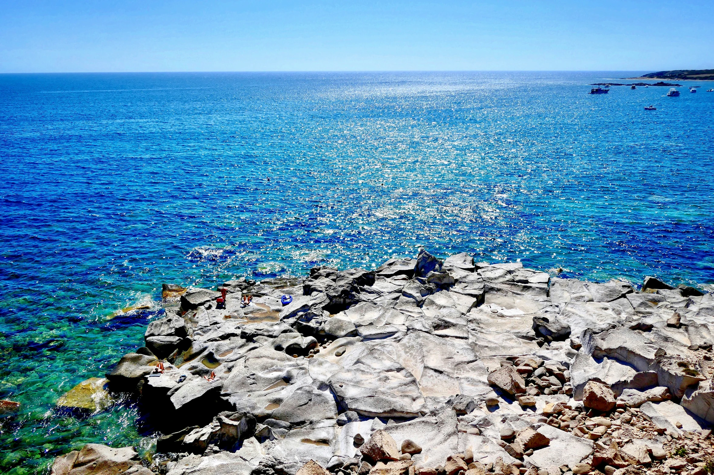 a lone boat out on the ocean by rocks