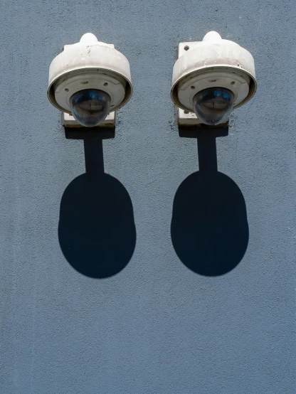 two surveillance cameras facing one another in shadow