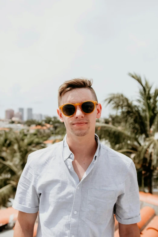 a young man wearing sunglasses standing on a roof