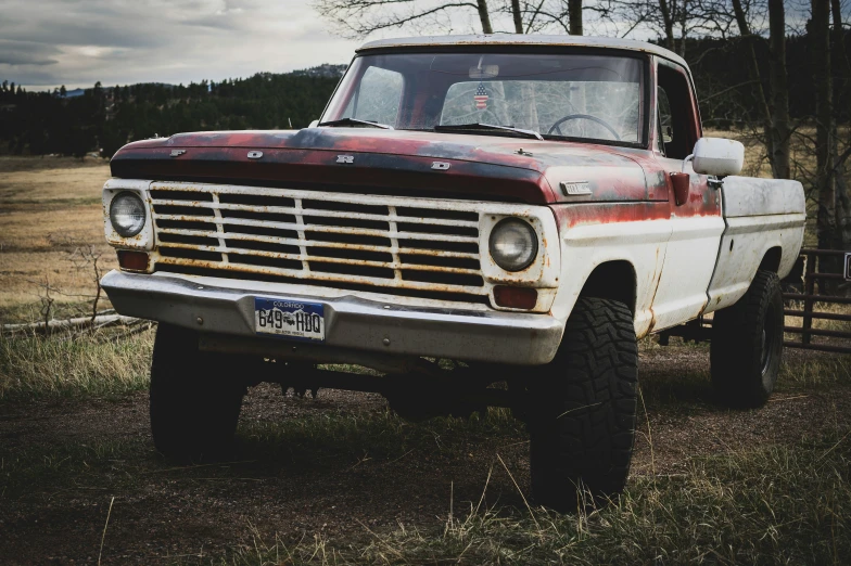 an old, rusty red truck is parked in the grass