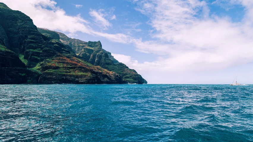 a boat is riding along the water near mountains