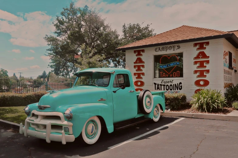 an antique green truck is parked in front of a taco restaurant