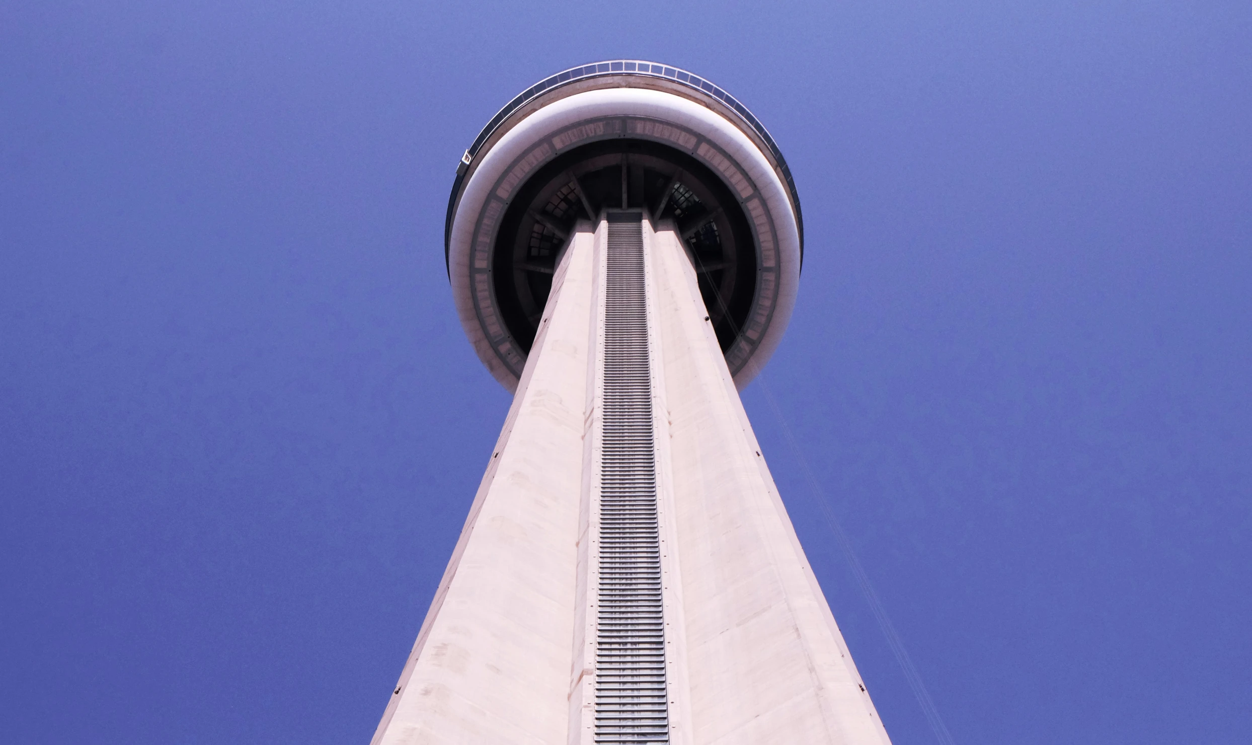 the space needle is shown from below and a bright blue sky is seen behind