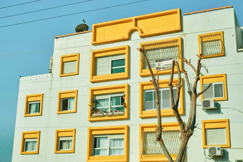 a tall yellow and white building sitting under a blue sky