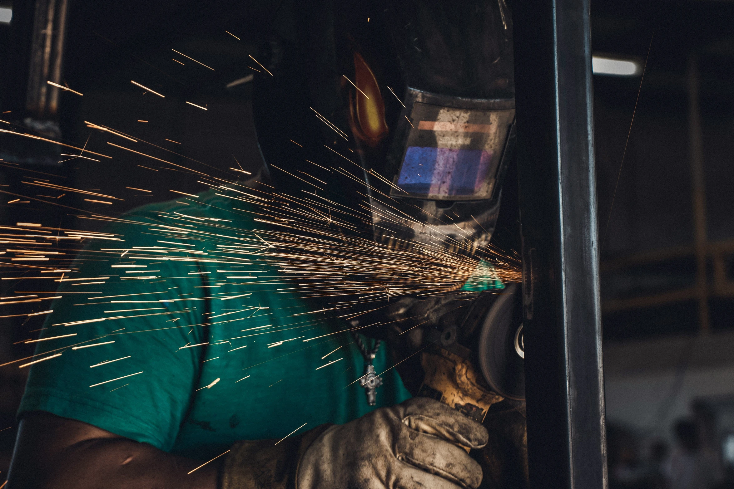 welder wearing green shirt  metal rods