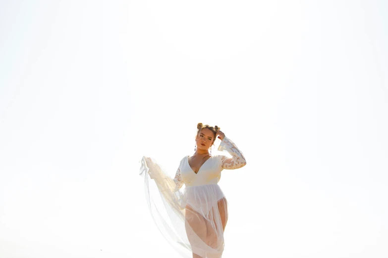 a woman wearing a white bathing suit while standing on the beach