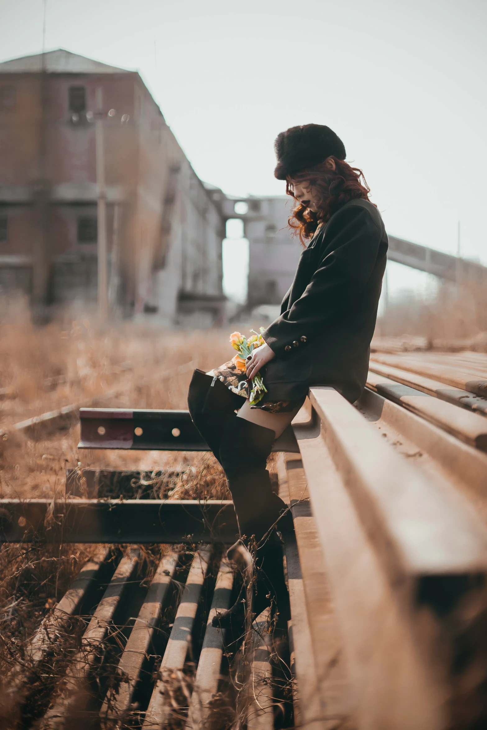 a man sitting on a bench by the railroad tracks
