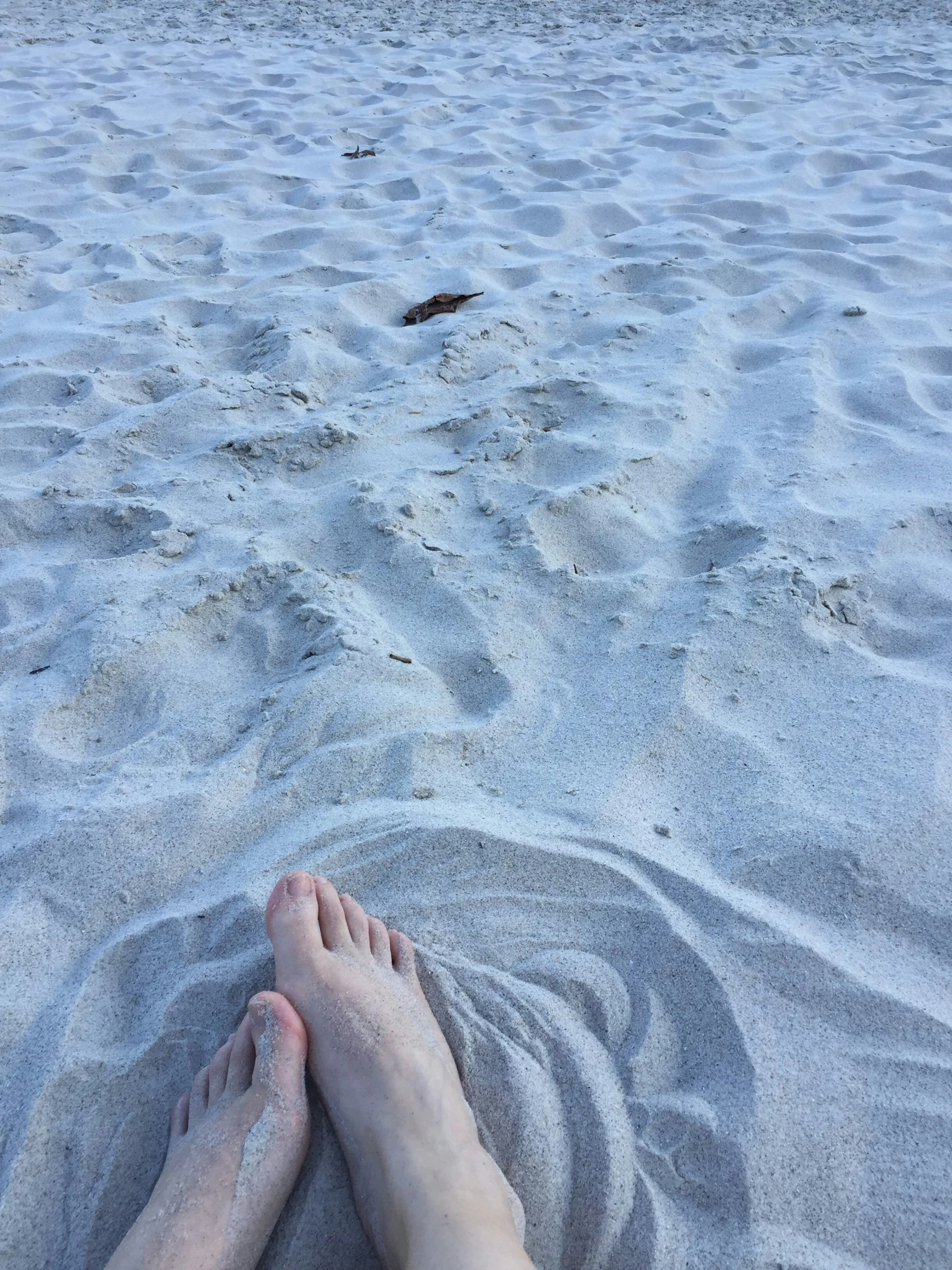 a person is laying down on a beach in the sand