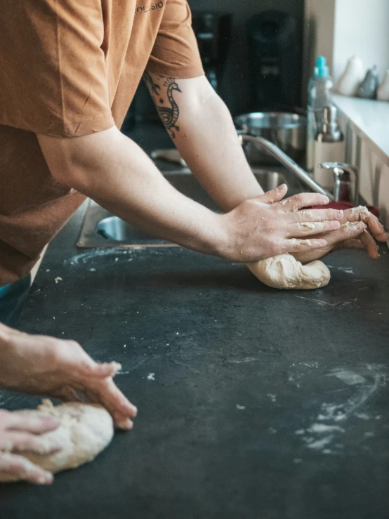 two people kneading dough in a kitchen