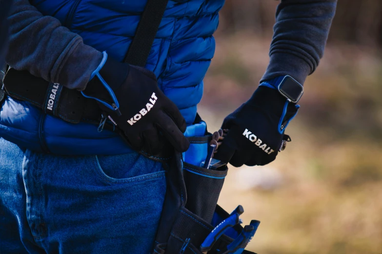 a man wearing winter gloves and a blue jacket