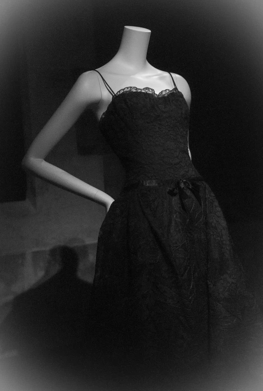 a mannequin stands next to a black dress with white lace