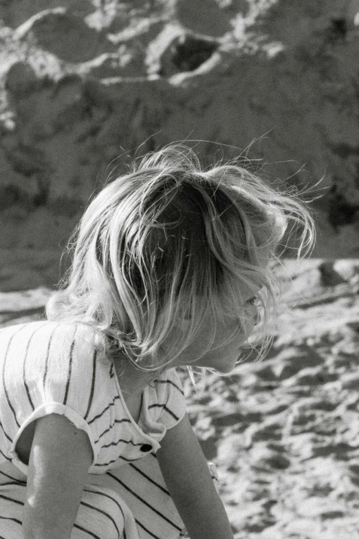 young child sitting on the beach, facing away