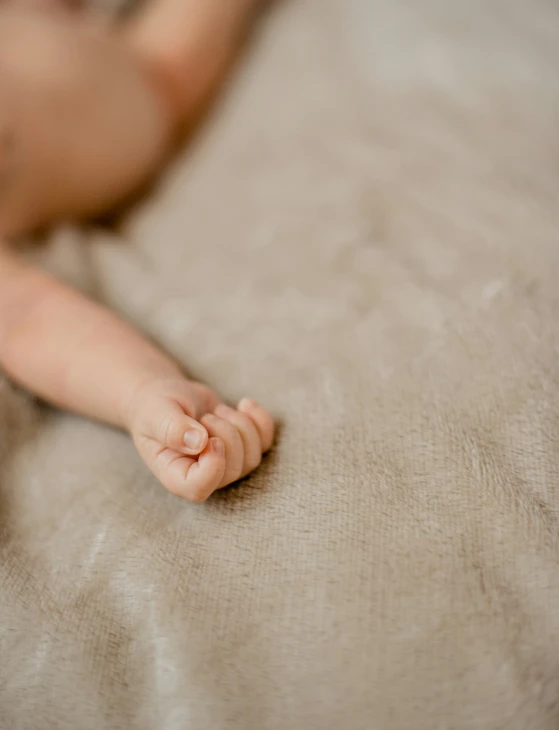 a closeup of the top of a hand on a bed