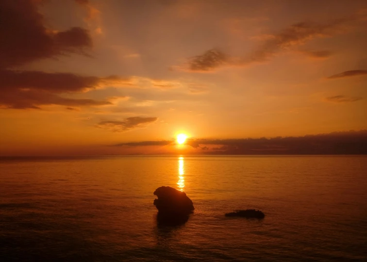 a person on the beach at sunset sitting in the water