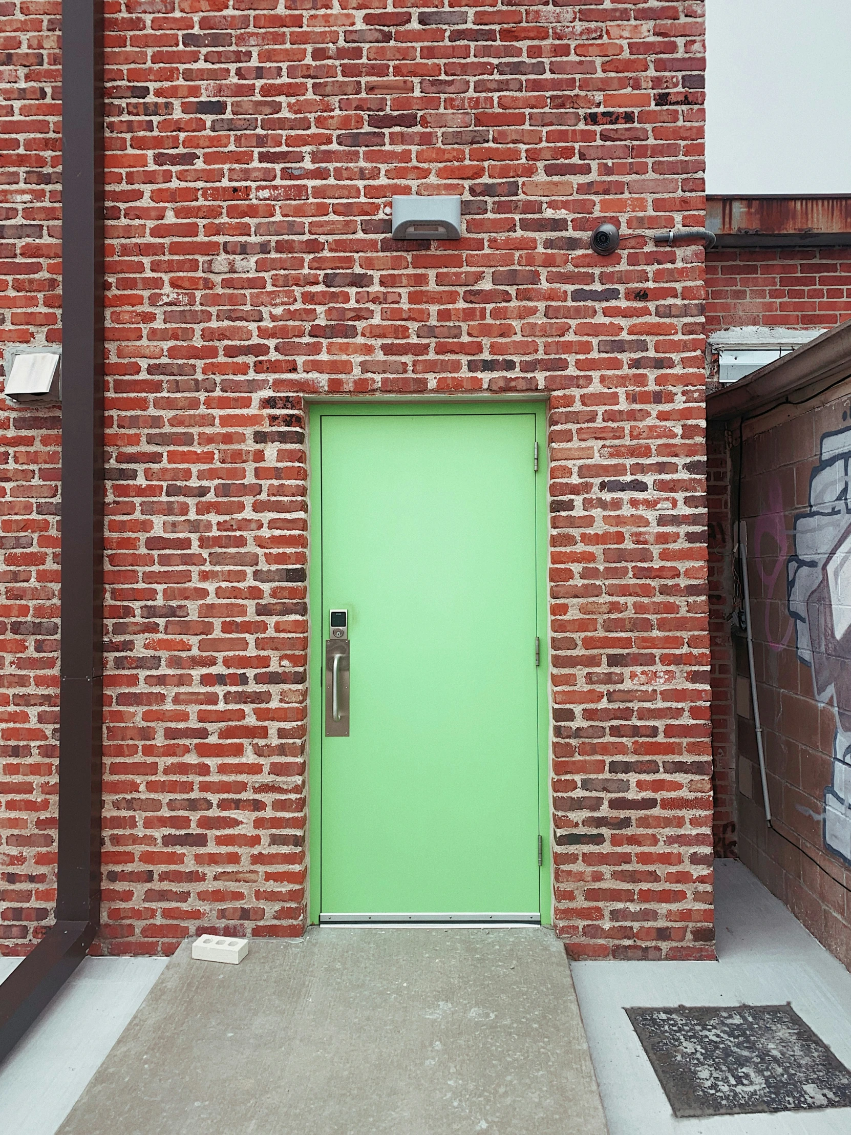 a green door is between two brick buildings