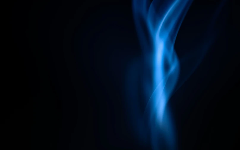 a dark background with blue smoke in the air