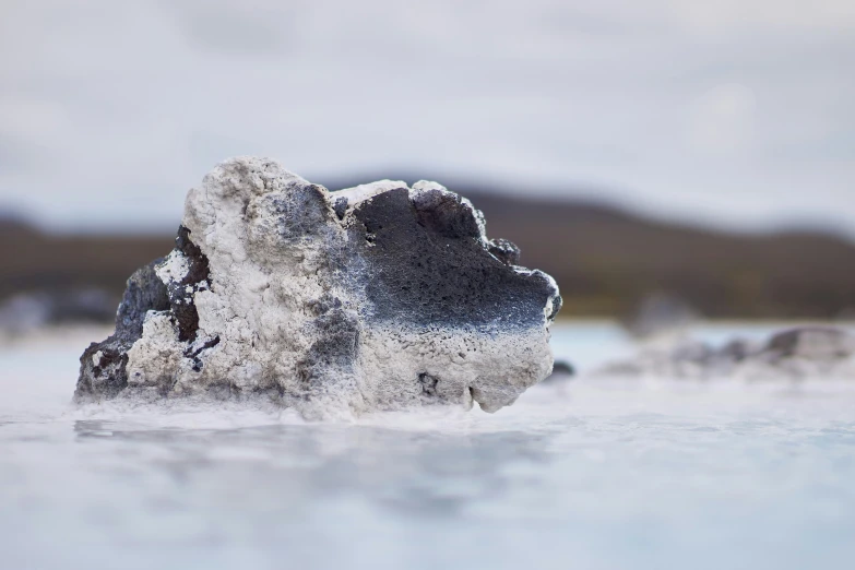 a snow covered stone in some shallow water