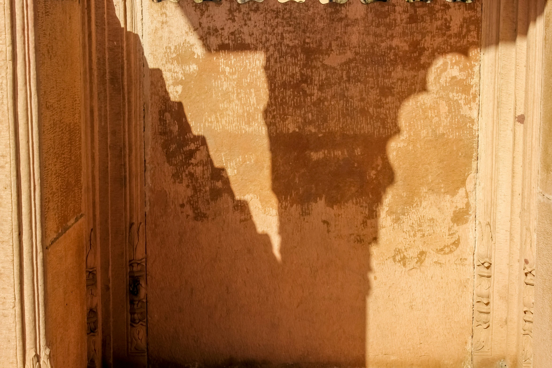 the shadow of a clock on the wall behind a door