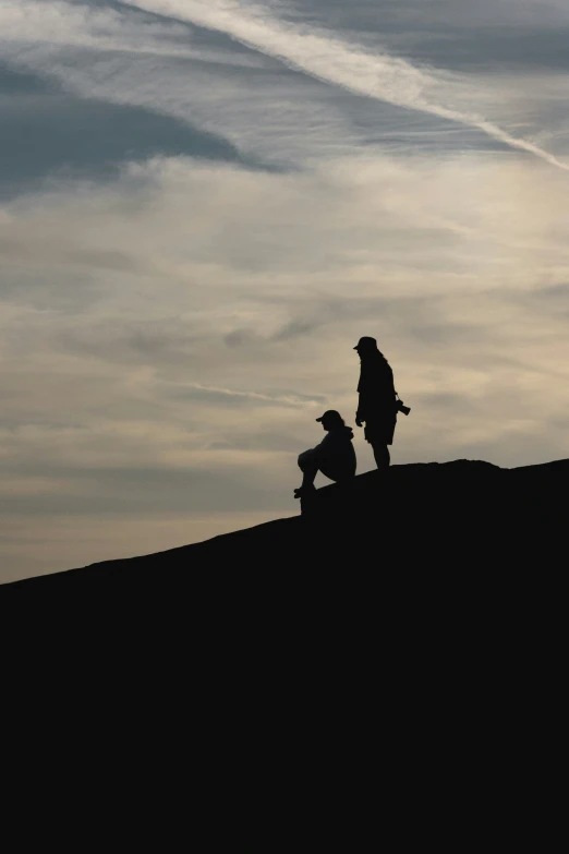 two people are standing on top of a hill