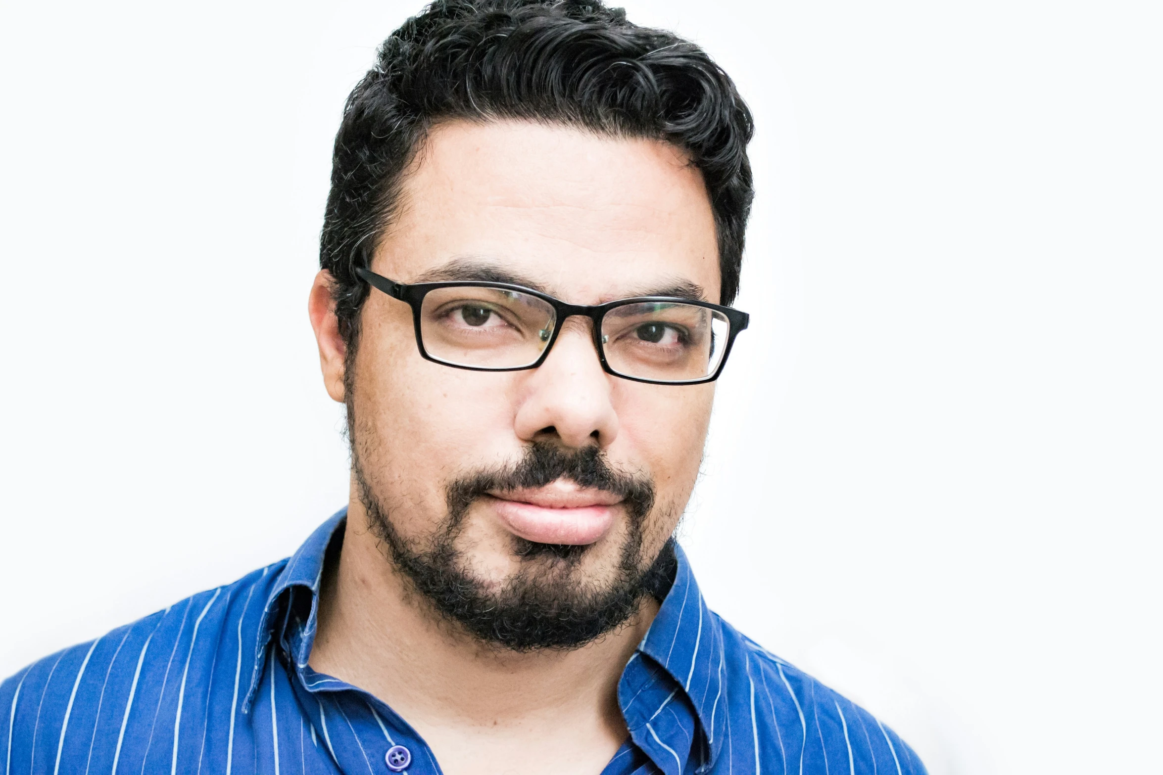 a man with glasses and beard wearing a blue shirt