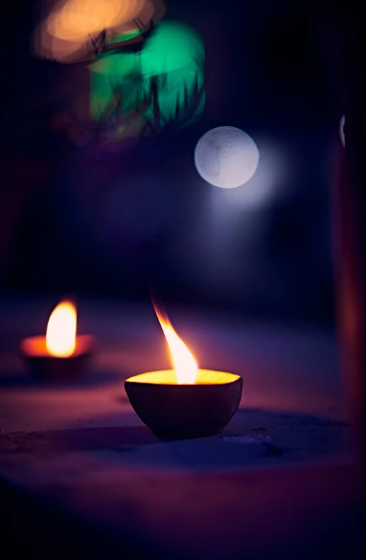 small candles in a bowl in front of bokeh of blurred objects