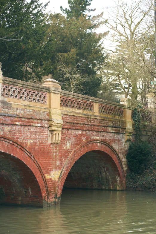 bridge over water with red brick overhangs and railing