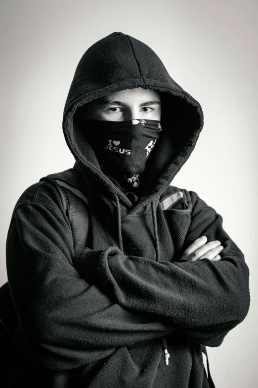 an asian man with a mask, hoodie and arms crossed