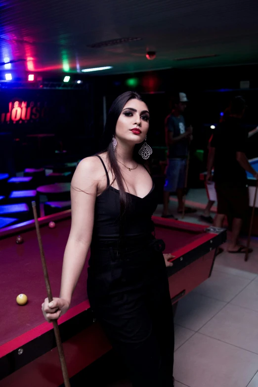 a woman in black holding a pool stick
