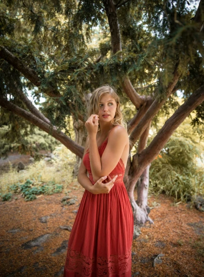 a beautiful young woman standing under a tree