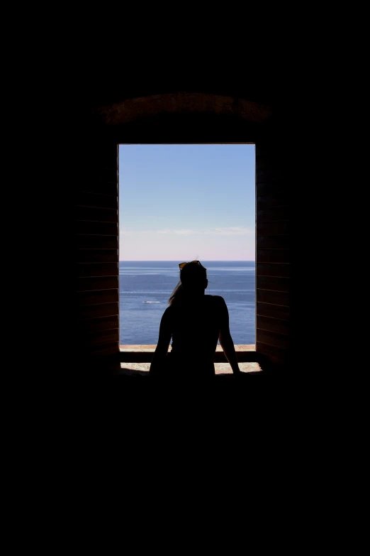 the silhouette of a woman is standing in an open window
