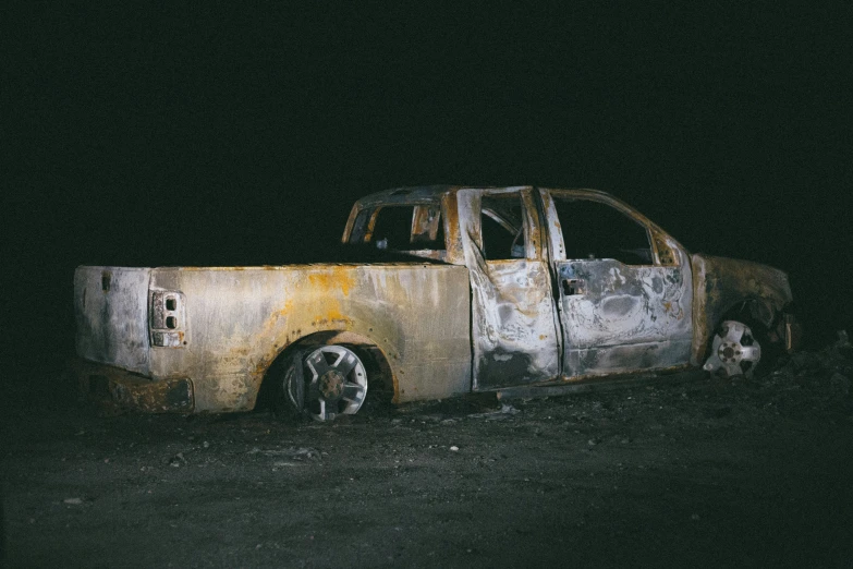 there is a old rusted truck sitting in the dark