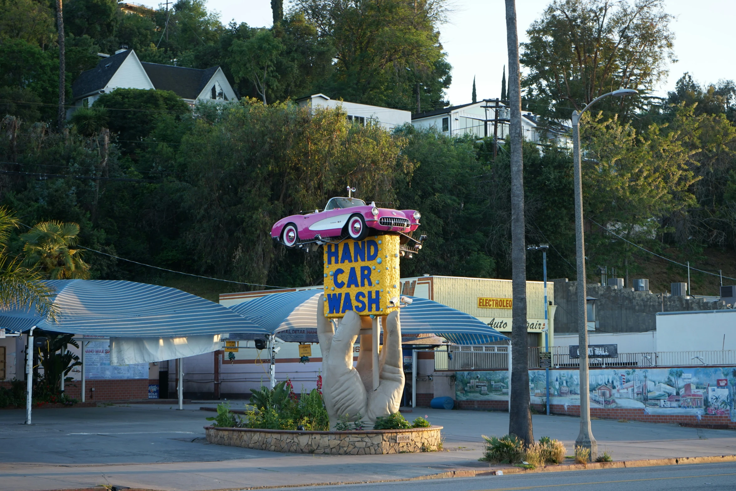 a pink car sits atop a yellow sign next to a parking lot