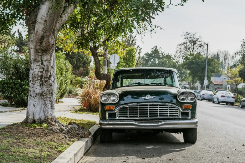 an old fashioned green car parked in front of trees