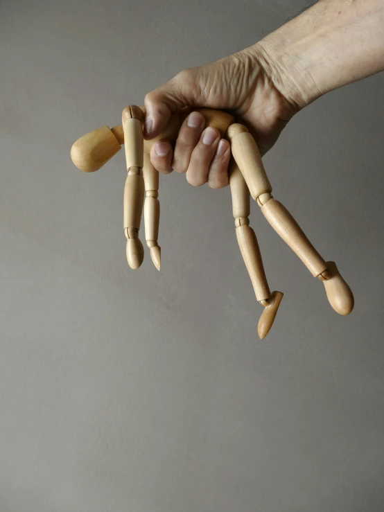 hand holding a doll made from wooden pegs
